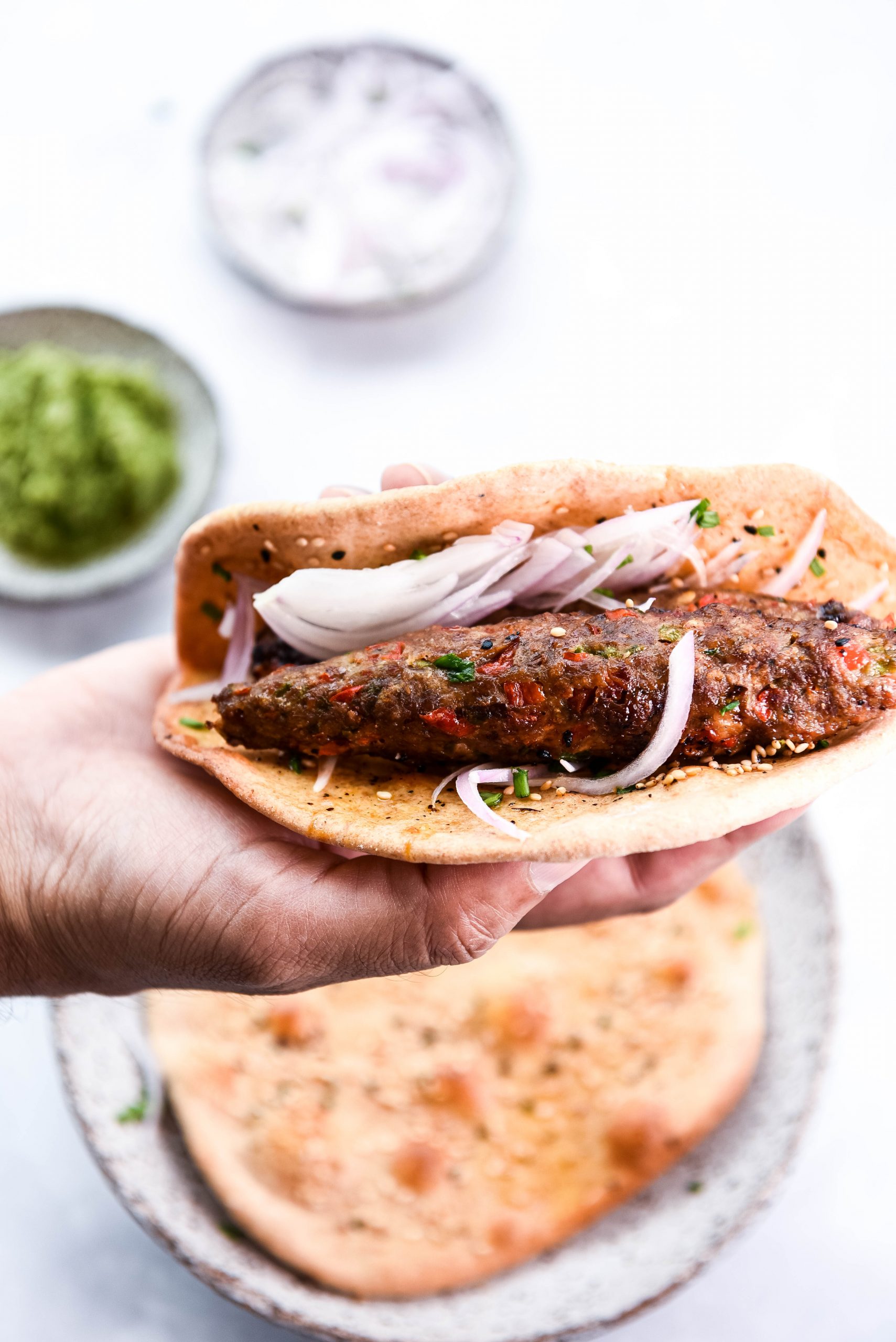 3 plate and a hand holding a shish kebab wrap